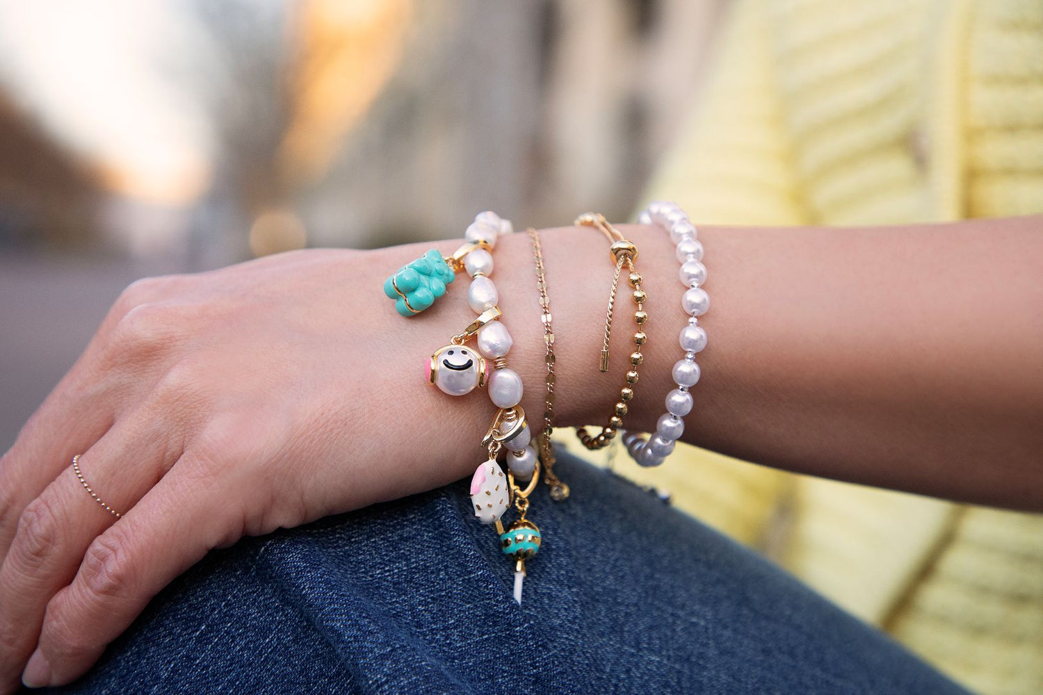 Close-up of a wrist wearing multiple bracelets with various charms.